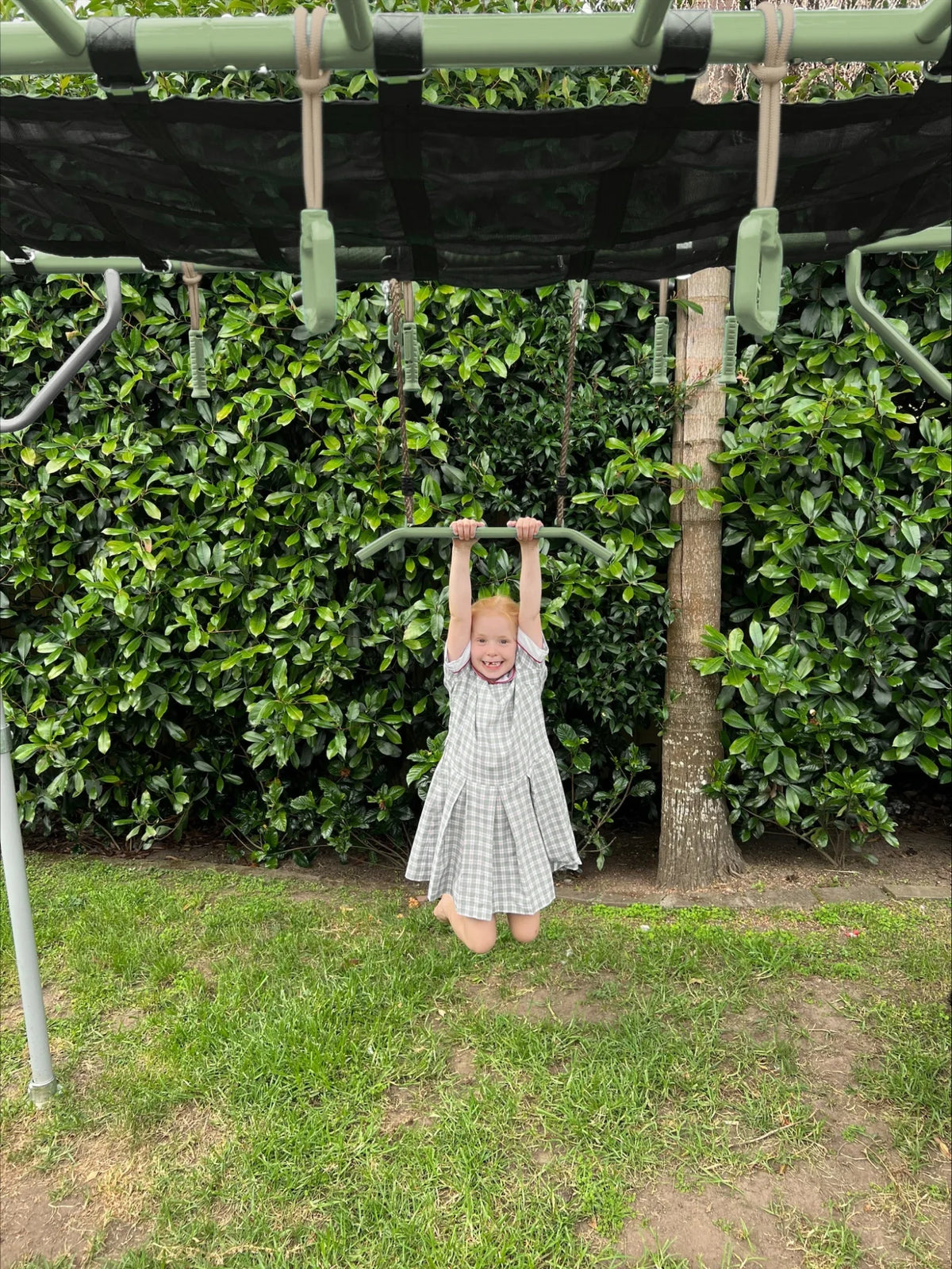 Trapeze in use on a Growplay frame in a family garden